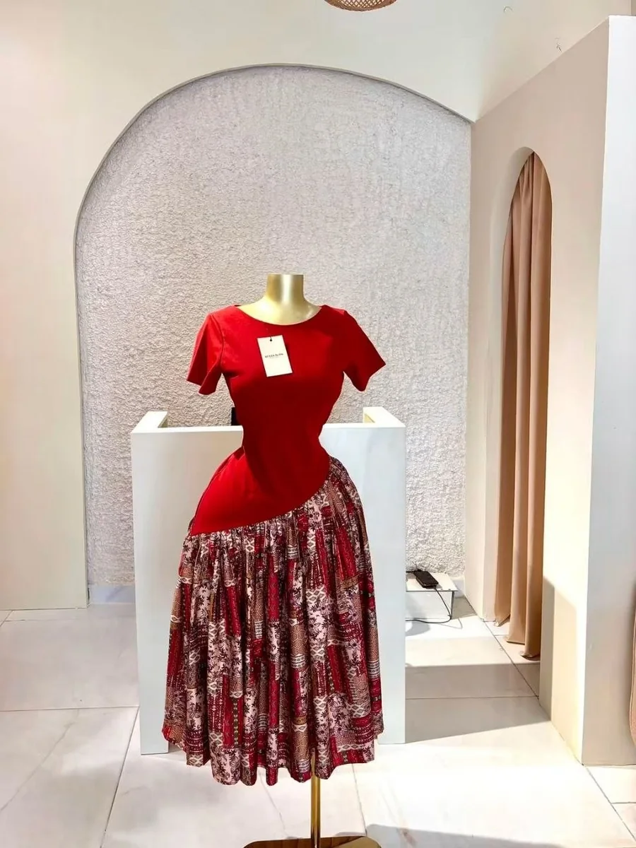 Une robe sur son socle doré, devant l’arche blanche de la boutique